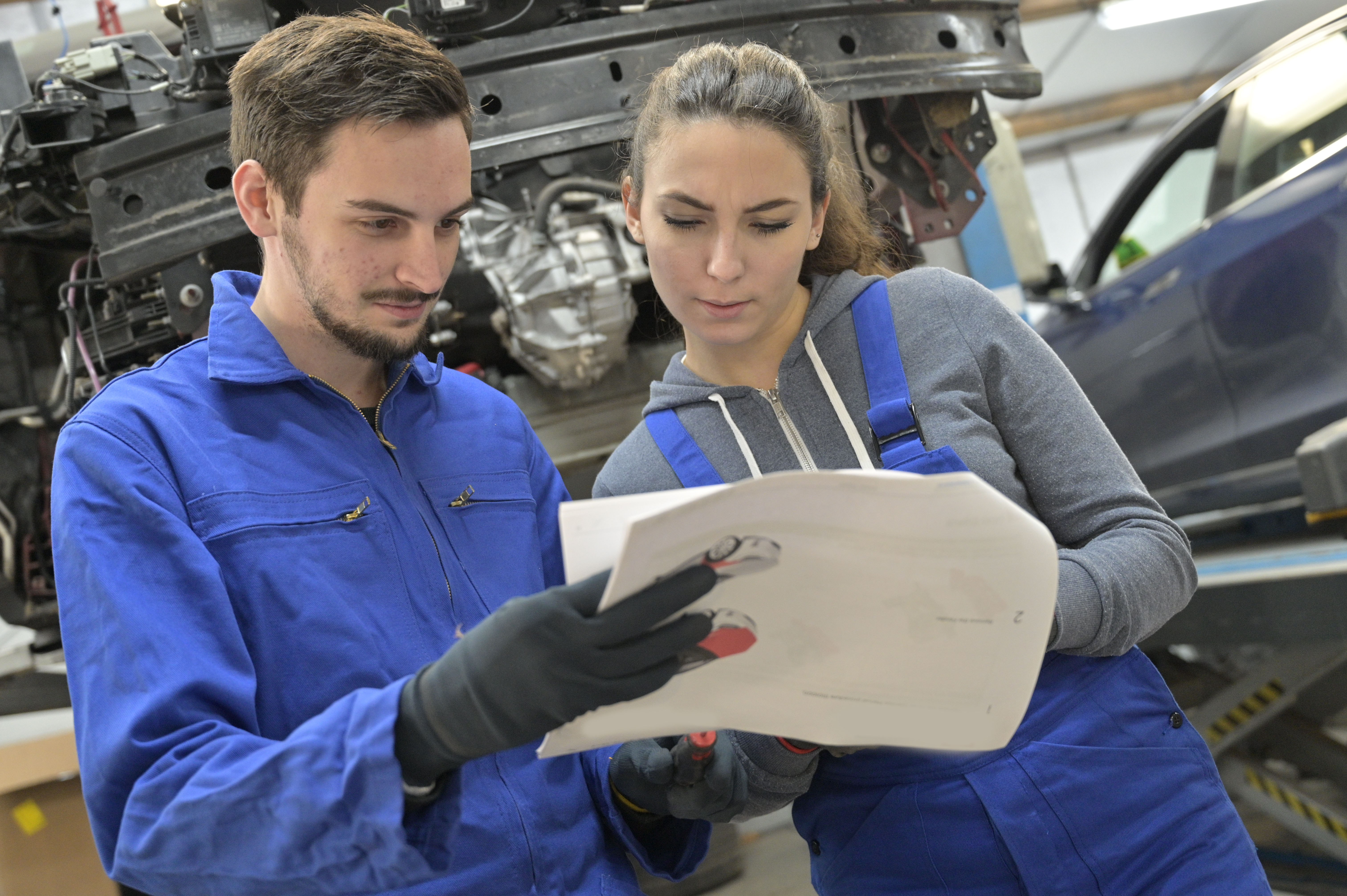 Young man and woman reviewing auto design plans in a shop.